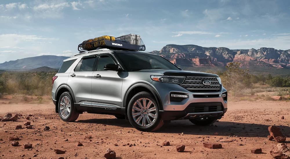 A silver 2023 Ford Explorer with a loaded roof rack is shown embarking on its first overlanding expedition through the desert after leaving a Ford Explorer dealer.