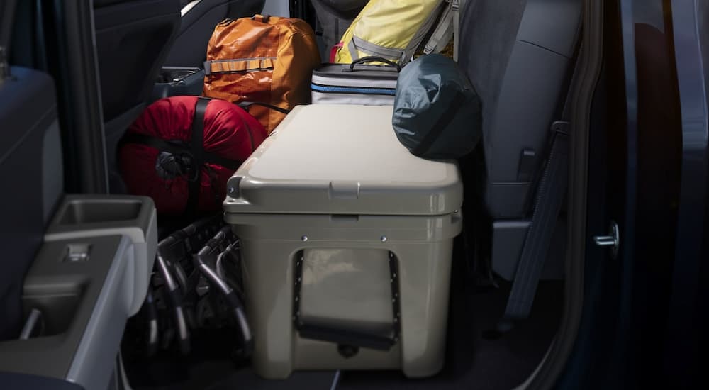 The rear seat of a 2023 Ford F-150 is shown loaded with off-road gear.