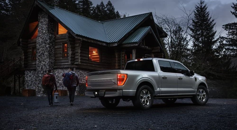 A silver 2023 Ford F-150 Platinum is shown parked near a cabin.