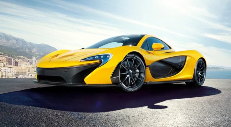 A yellow and black 2013 McLaren P1 Hybrid is shown parked near a city.
