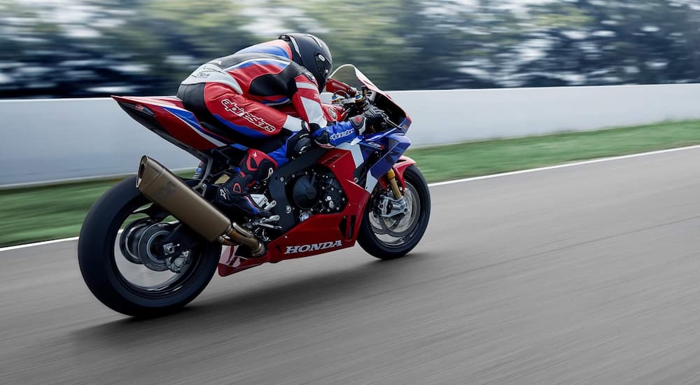 A red, white, and blue 2021 Honda CBR1000RR-R Fireblade SP is shown accelerating at the track.