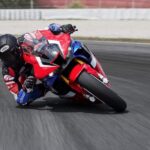 A red, white, and blue 2021 Honda CBR1000RR-R Fireblade SP, the top Honda CBR for sale, is shown cornering at the track.