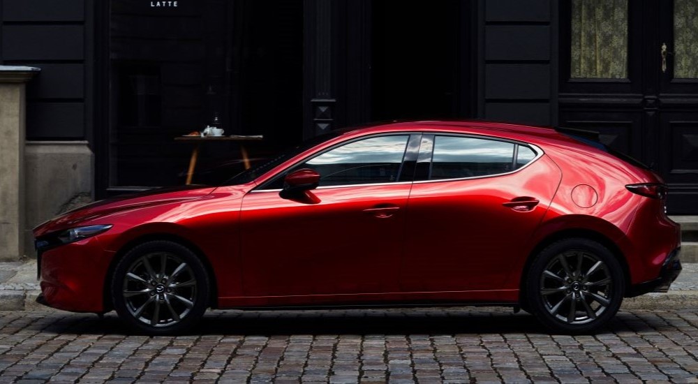 A red 2023 Mazda3 is shown parked on a street.