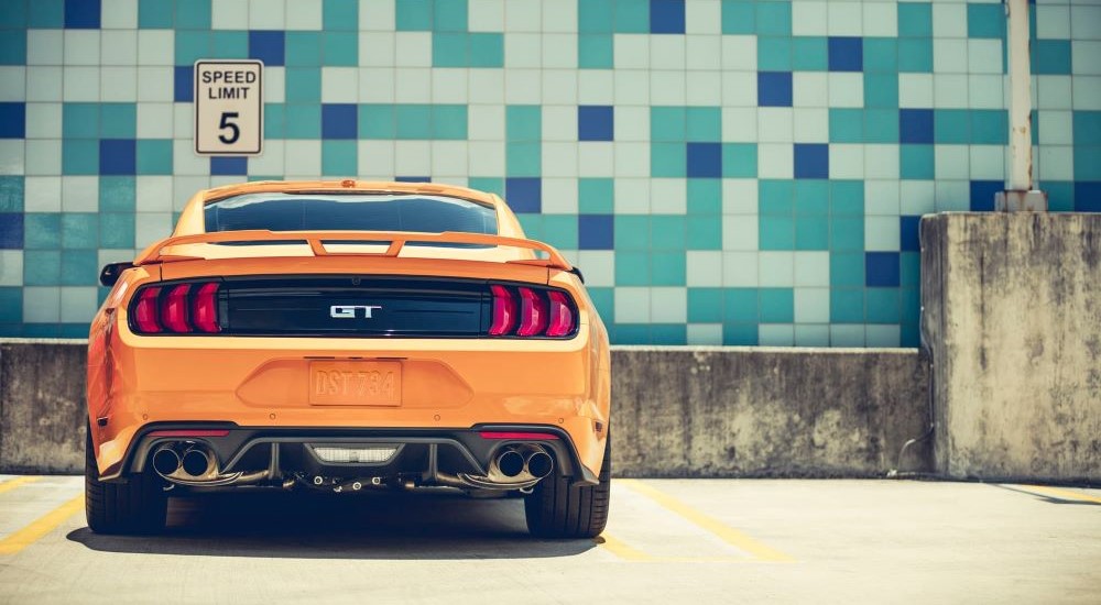An orange 2018 Ford Mustang GT is shown parked from the rear.