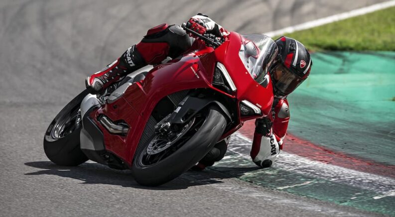 A red 2023 Ducati Panigale V2 is shown racing on a race track.