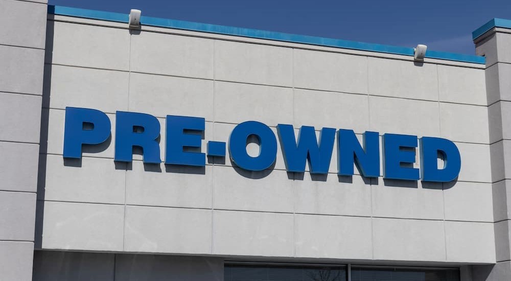 A pre-owned dealership sign is shown.