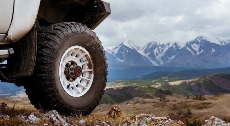 An off-road tire is shown near a mountain range.