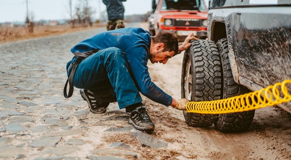 A man is shown using an air compressor to fill his tire with air. 