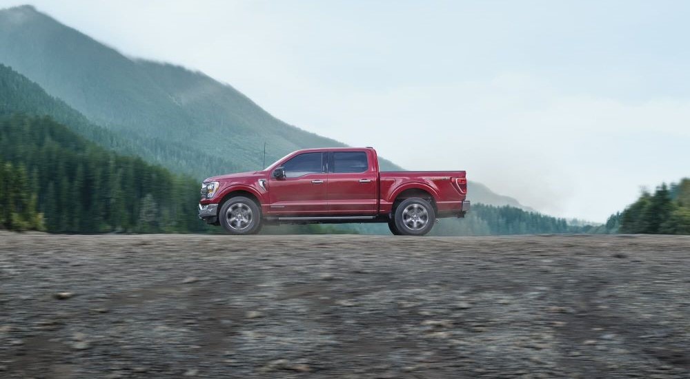 A red 2023 Ford F-150 is shown driving off-road.