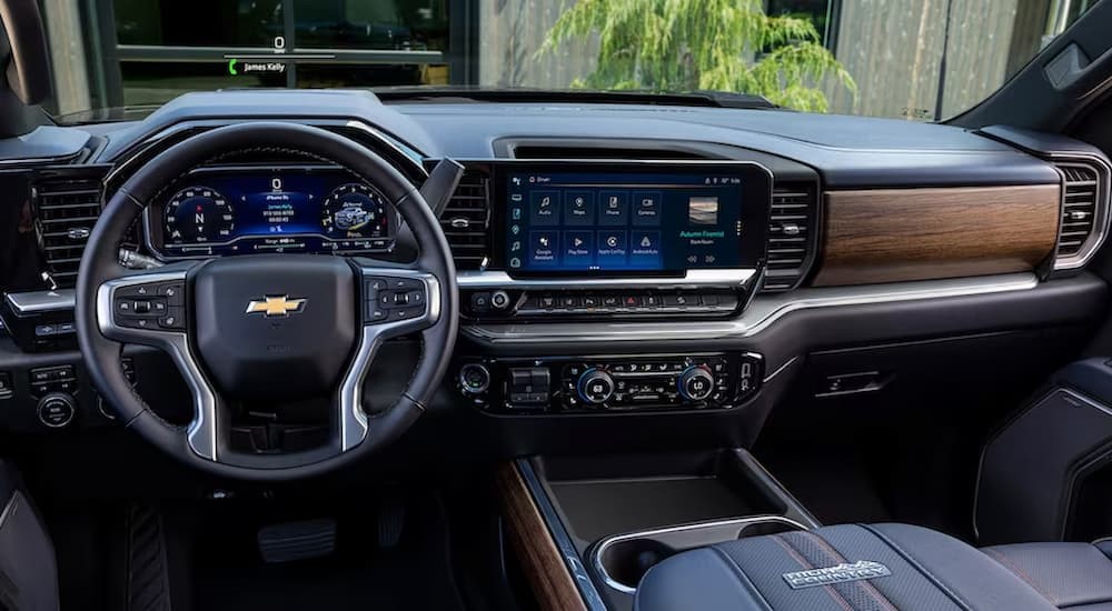 The gray and wood-grain interior and dash of a 2023 Chevy Silverado 2500 HD is shown.