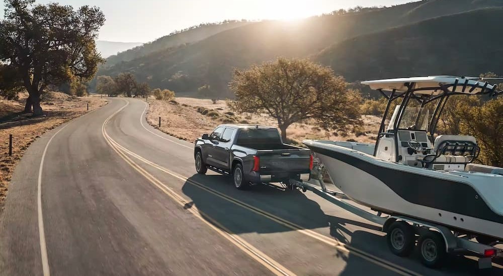 A gray 2023 Toyota Tundra is shown towing a boat.