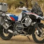 A white BMW R 1250 GD Adventure is shown parked off-road.