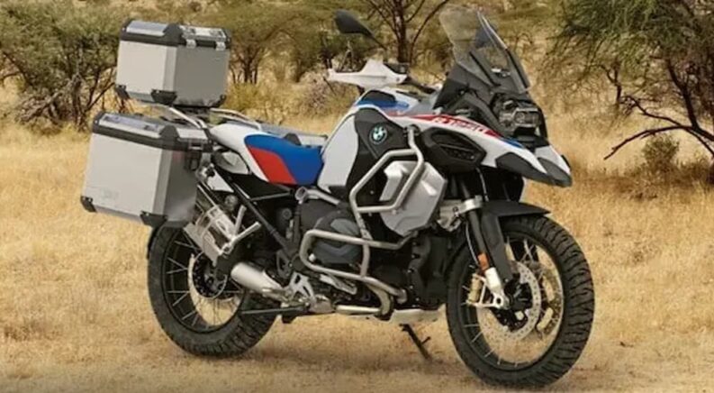 A white BMW R 1250 GD Adventure is shown parked off-road.
