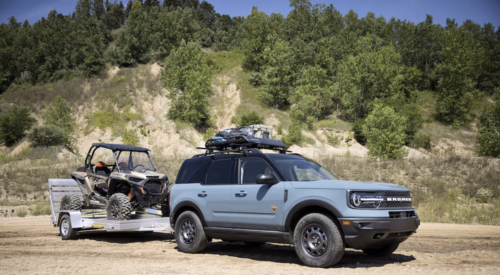 A grey 2022 Ford Bronco Sport Badlands is shown from the side while towing a UTV.