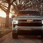 A silver 2023 Chevy Silverado 1500 is shown driving on a dirt road after viewing a Chevy Silverado for sale nearby.