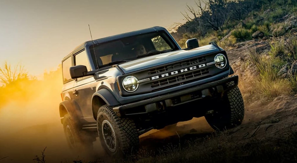 A blue 2023 Ford Bronco is shown driving off-road.