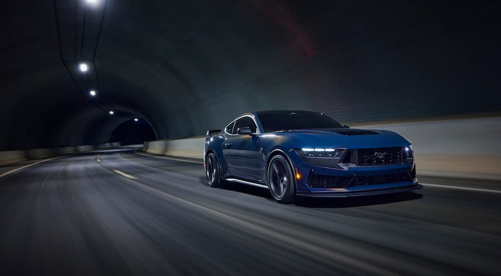 A blue 2024 Ford Mustang Dark Horse is shown from the front at an angle after leaving a dealer that has a 2023 Ford Mustang for sale.