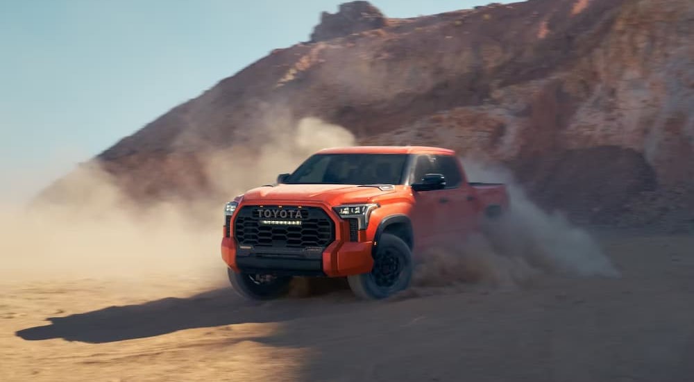 An orange 2023 Toyota Tundra is shown off-roading.