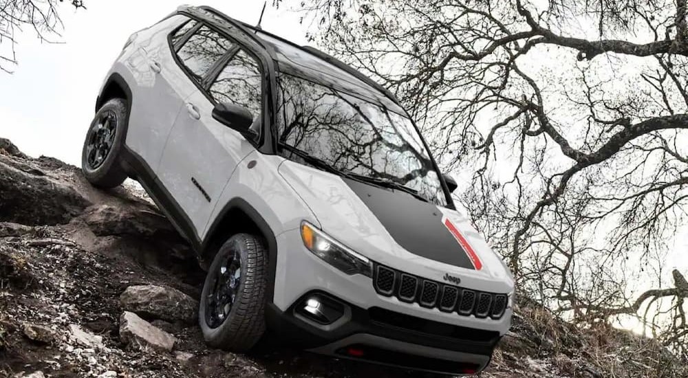 A white and black 2023 Jeep Compass Trailhawk is shown descending on a rocky decline.