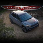 A blue 2023 Jeep Compass Trailhawk is shown on a dirt path.