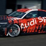A red and black 2021 Audi RS 3 LMS is shown driving to demonstrate "what is Touring Car Racing."
