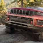 A red 2022 Jeep Grand Cherokee Trailhawk is shown from the front after leaving a Jeep dealer.