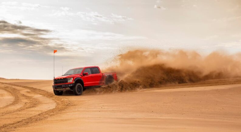 A red 2023 Ford F-150 Raptor R is shown from the side while off-road.