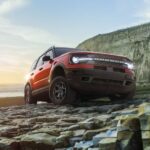 A red 2023 Ford Bronco Sport is shown near the ocean.