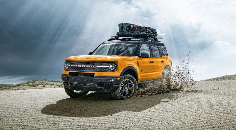 A yellow 2023 Ford Bronco Sport is shown kicking up sand on a sunny day.