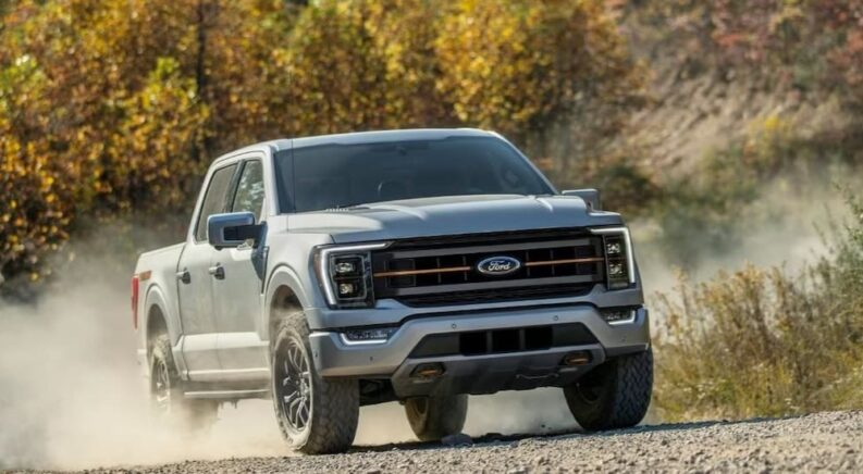 A silver 2023 Ford F-150 Tremor is shown driving on a dirt road after winning a 2023 Ford F-150 vs 2023 Ram 1500 comparison.