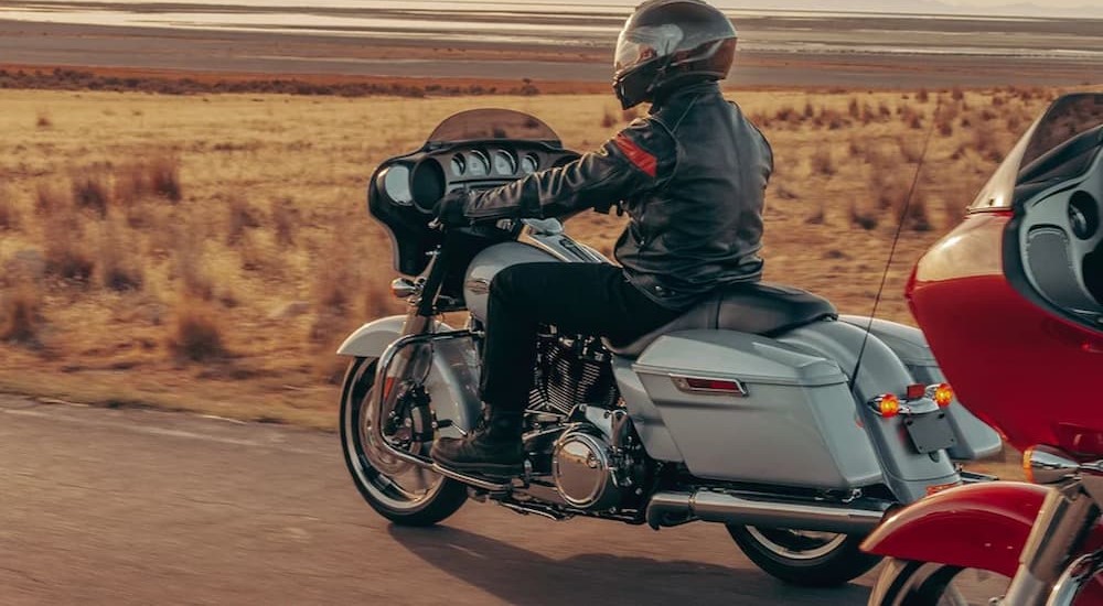 A silver 2023 Harley-Davidson Street Glide is shown riding on a road.