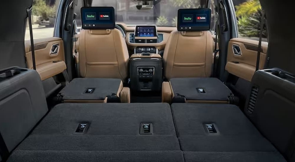The tan and gray interior, dash, and cargo space of a 2023 Chevy Suburban is shown.