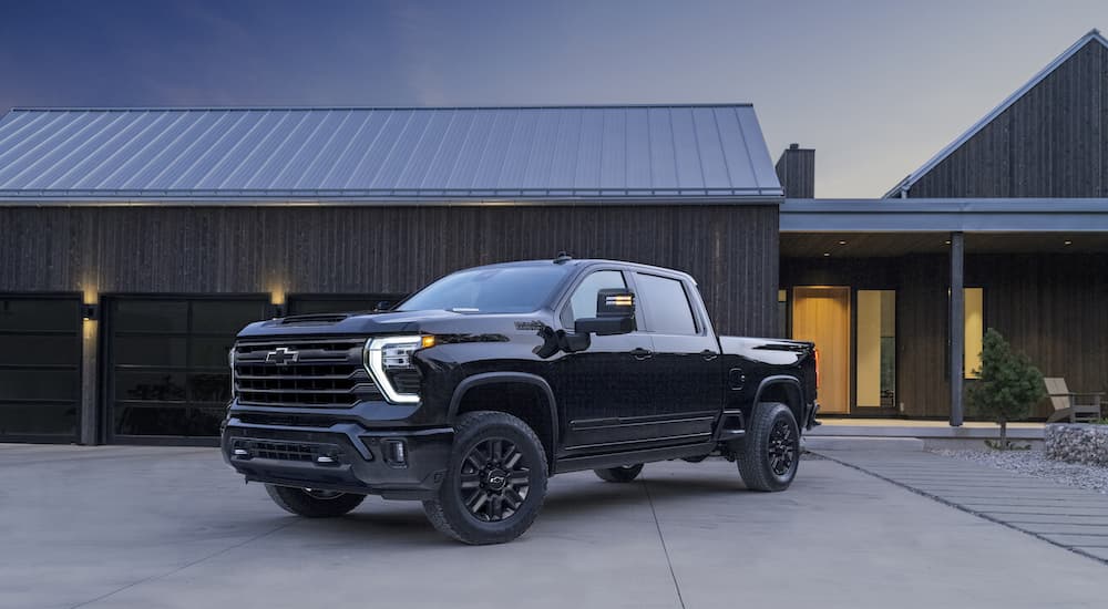 A black 2024 Chevy Silverado 2500 HD High Country Midnight Edition is shown from the front at an angle in a driveway.