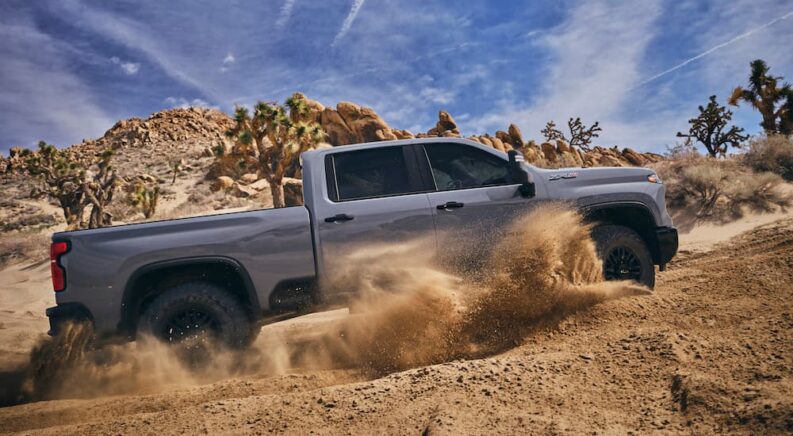 A silver 2024 Chevy Silverado 2500 HD ZR2 is shown from the side while off-road.