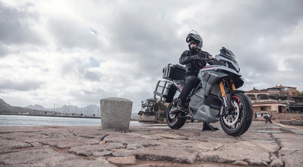 A gray 2023 Energica Experia is shown parked near a lake.