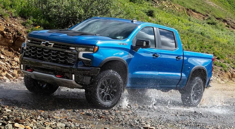 A blue 2024 Chevy Silverado 1400 ZR2 is shown driving off-road.