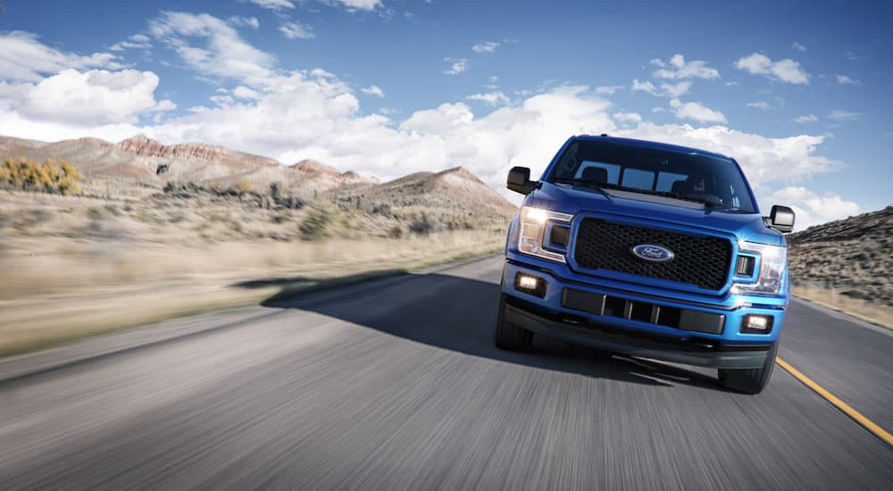 A blue 2018 Ford F-150 is shown driving on a highway after visiting a Ford dealership.