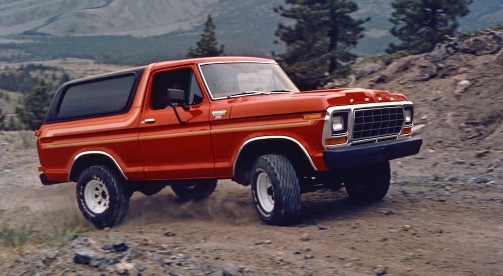 A red 1978 Ford Bronco is shown off-roading.
