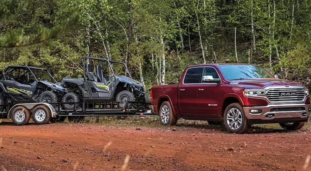 A red 2023 Ram 1500 is shown towing a trailer.