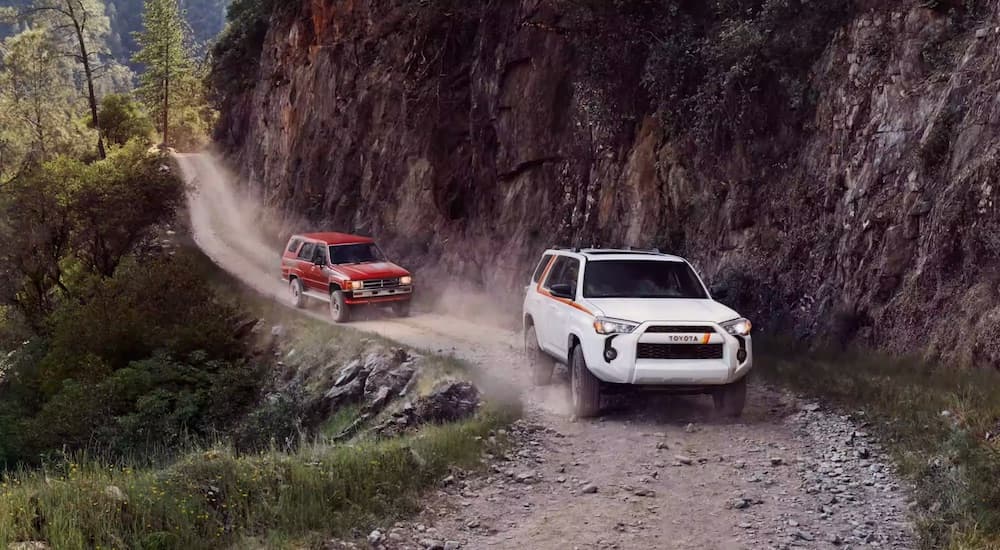 A white 2023 Toyota 4Runner 40th Anniversary Edition is shown off-roading near a red SUV.
