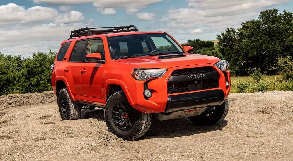 An orange 2023 Toyota 4Runner TRD is shown parked off-road after visiting a Toyota dealer.