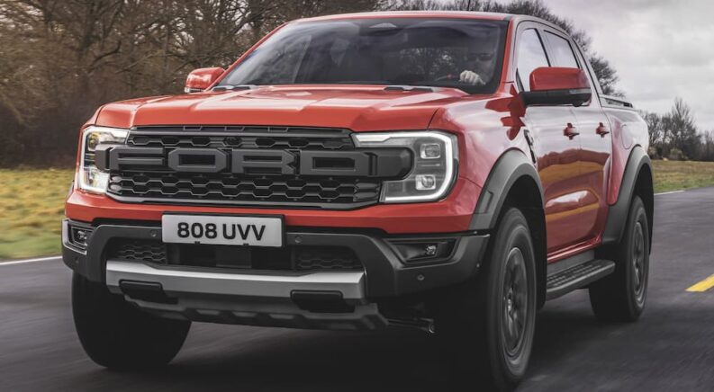 An orange 2024 Ford Ranger Raptor is shown from the front at an angle.