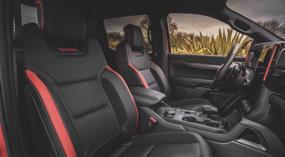 The black and red interior of a 2024 Ford Ranger Raptor is shown from the passenger side.