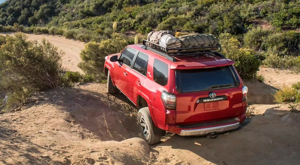 A red 2023 Toyota 4Runner TRD is shown driving off-road on dirt.