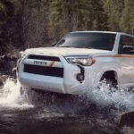 A white 2023 Toyota 4Runner 40th Anniversary Special Edition is shown driving off-road on water.