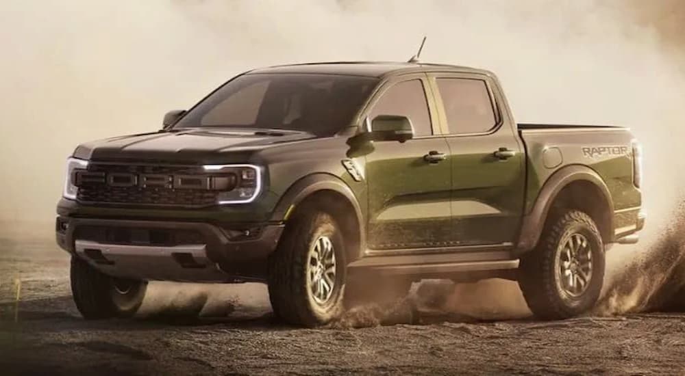 A 2024 Ford Ranger Raptor is shown driving off-road in a sandy area.