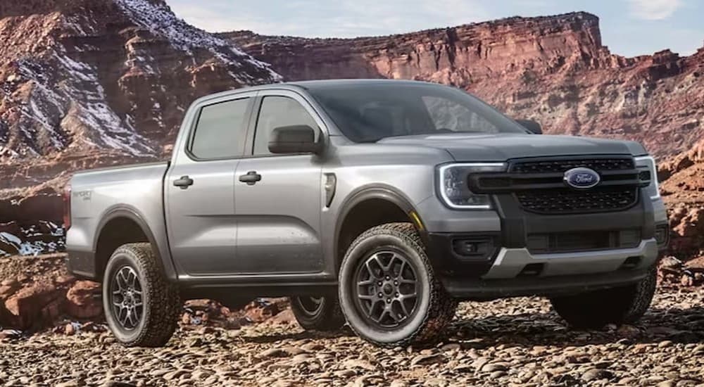 A silver 2024 Ford Ranger is shown parked off-road on dirt.