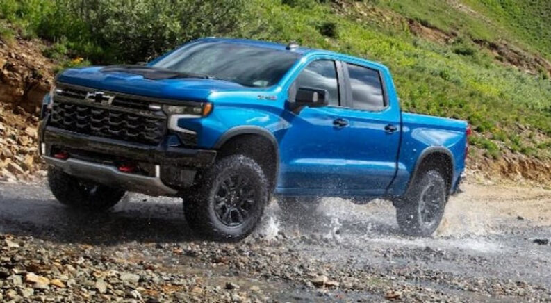 A blue 2024 Chevy Silverado 1500 ZR2 is shown off-roading on water.
