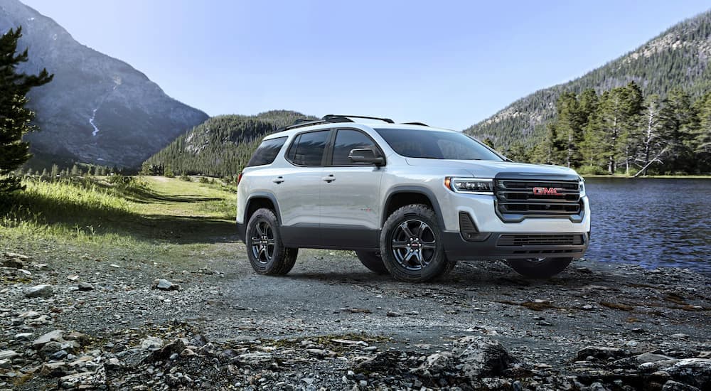 A white 2023 GMC Acadia AT4 is shown parked near a lake.