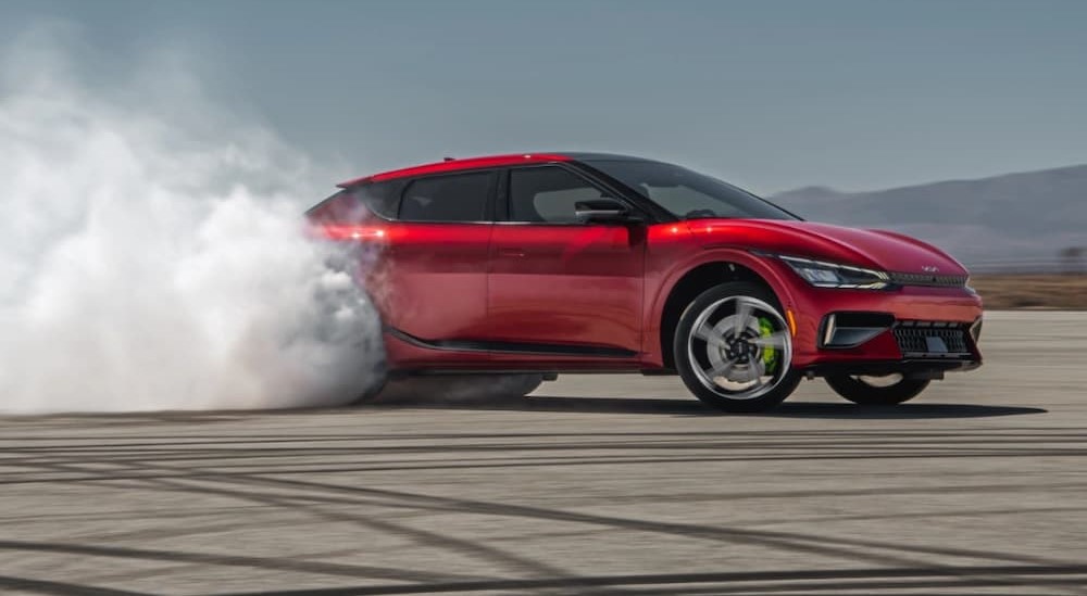 A red 2023 Kia EV6 is shown smoking the rear tires.